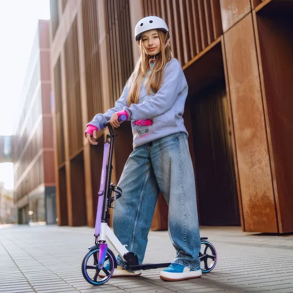 Dievča v cyklistickej prilbe stojí vonku na chodníku s detskou kolobežkou